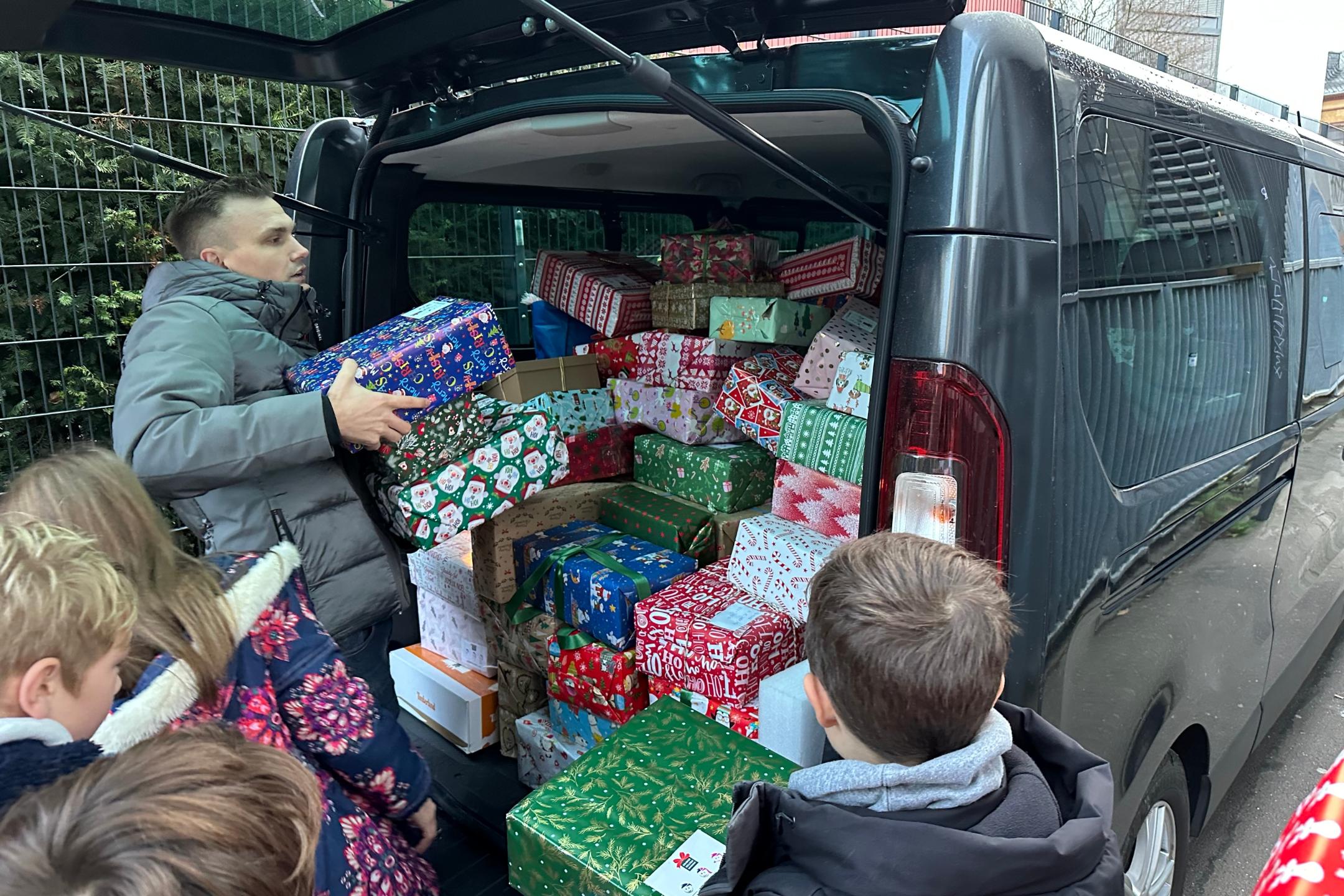 Kinder der GS am Dom beladen mit Herrn Dauns (Round Table Deutschland) einen Transporter mit Geschenken
