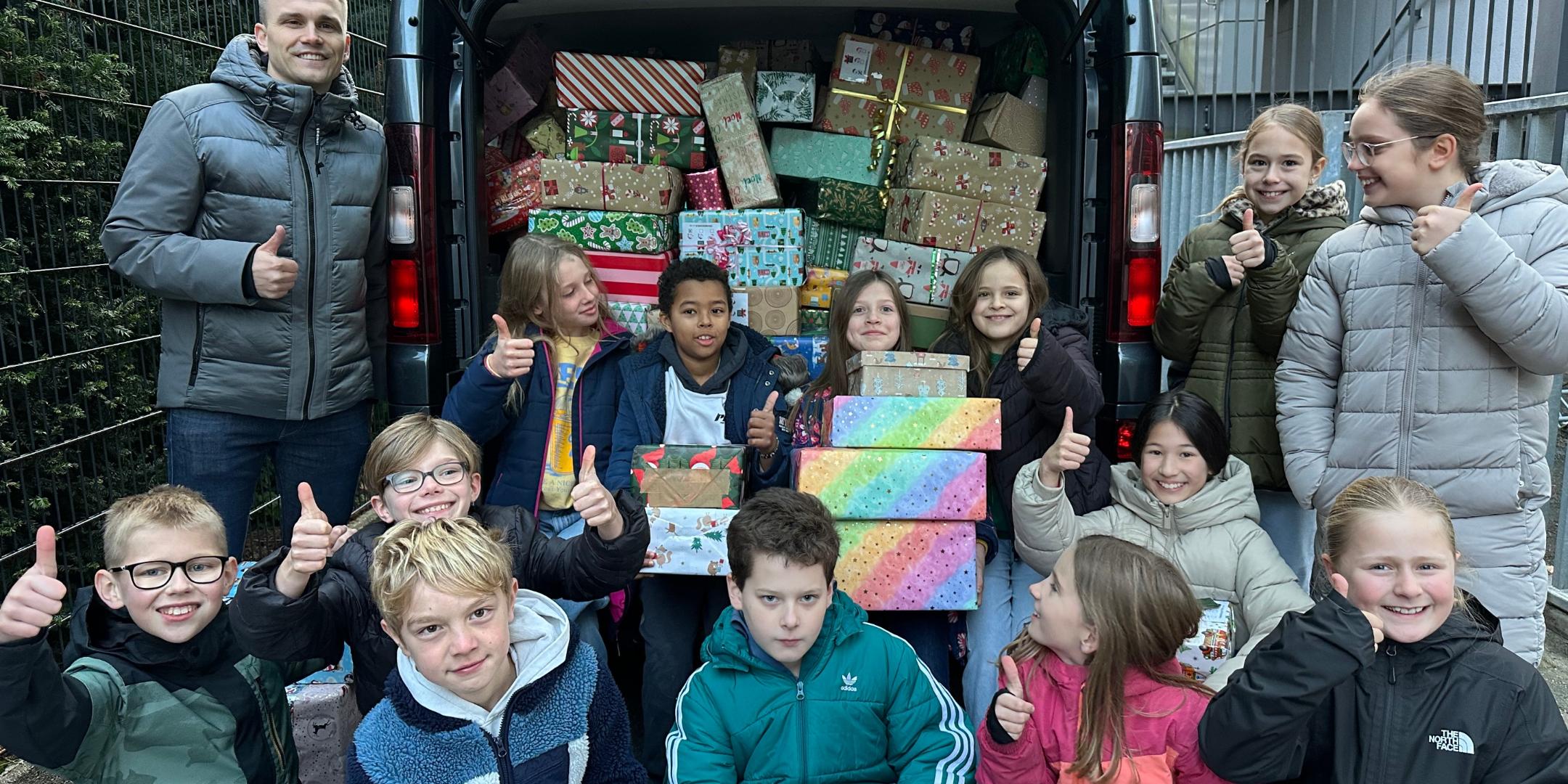 Herr Dauns (Round Table Deutschland) und Kinder der GS am Dom vor einem mit vielen Päckchen gefüllten Transporter