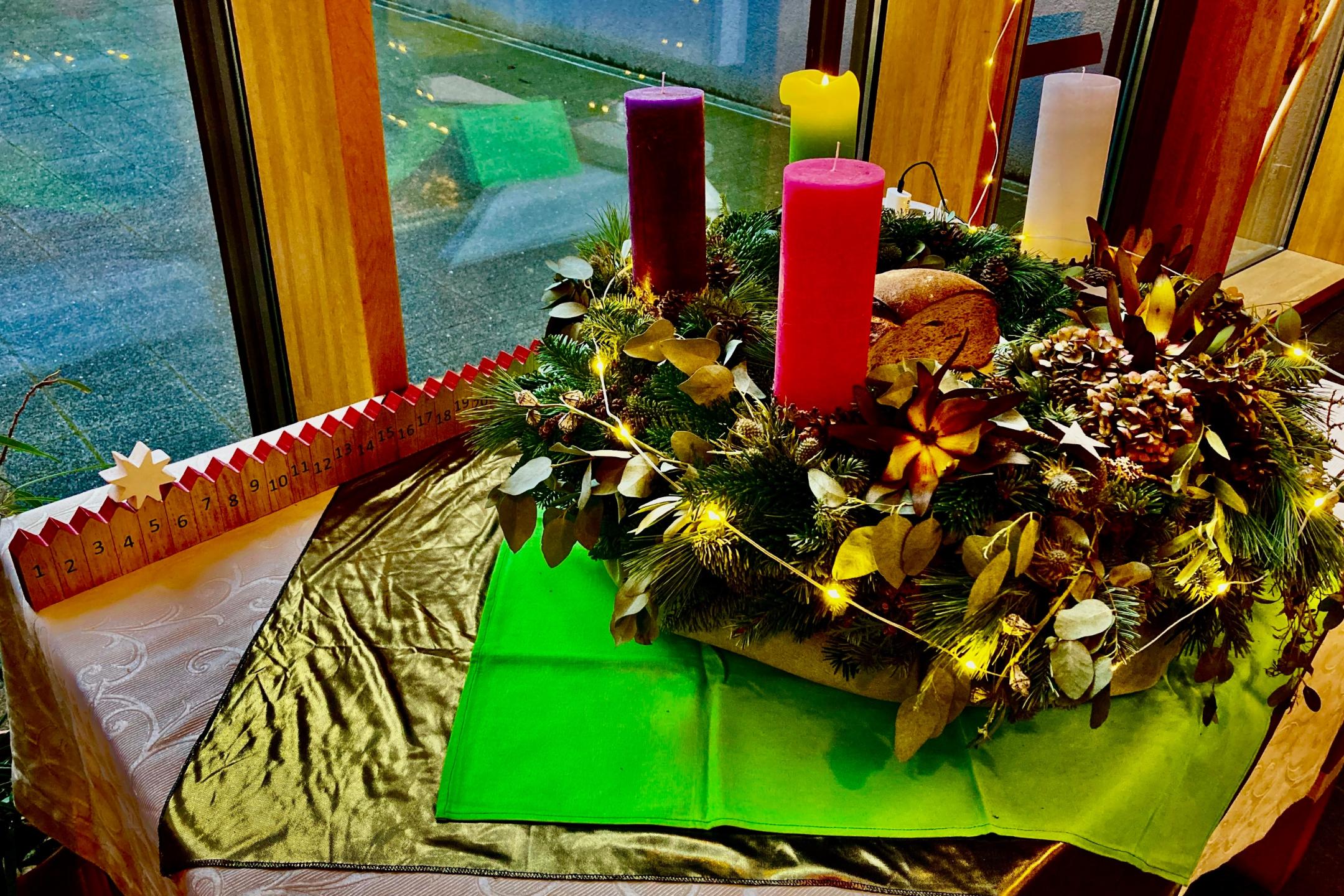 großer Adventskranz mit 4 Kerzen (grün, lila, rosa, weiß) auf dem Jahreszeitentisch im Foyer der GS am Dom