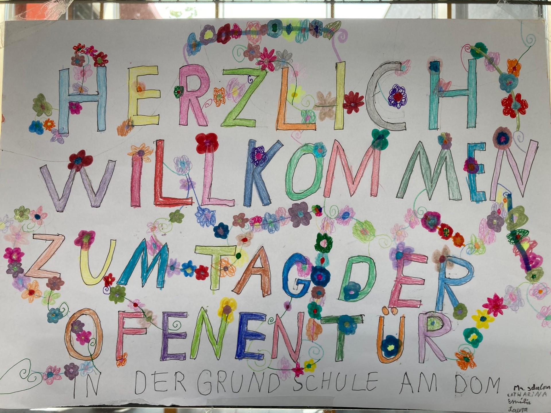 Man sieht ein von Kindern bunt gestaltetes Plakat mit der Aufschrift: Herzlich willkommen zum Tag der offenen Tür!